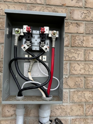 ACS Electricals technician installing a residential outdoor electric meter base on a brick home in Oakville.