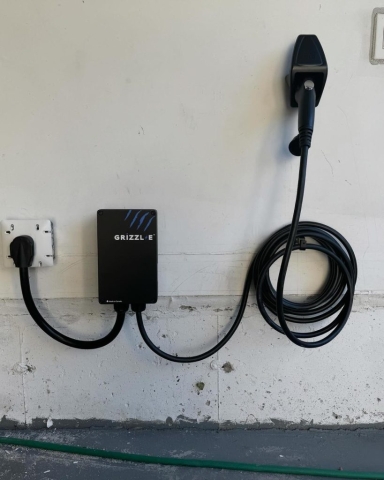ACS Electricals installer mounting a Grizzl-E Level 2 EV charging station inside a smart residential garage in Waterloo.